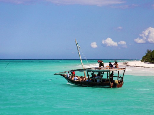 4 Days Zanzibar Paradise marine adventure. A sailboat glides across the turquoise waters of the Indian Ocean, with the white sandy beaches of Zanzibar in the distance.