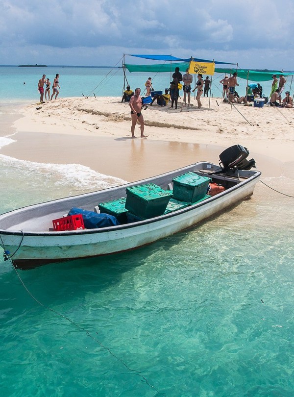 5 Days Zanzibar Ultimate Eco-Friendly Getaway. A breathtaking view of the Blue Lagoon in Zanzibar, featuring crystal-clear turquoise waters surrounded by lush greenery and white sandy shores.