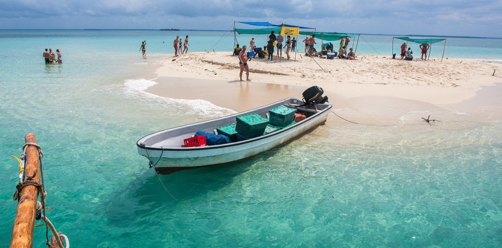 5 Days Zanzibar Ultimate Eco-Friendly Getaway. A breathtaking view of the Blue Lagoon in Zanzibar, featuring crystal-clear turquoise waters surrounded by lush greenery and white sandy shores.